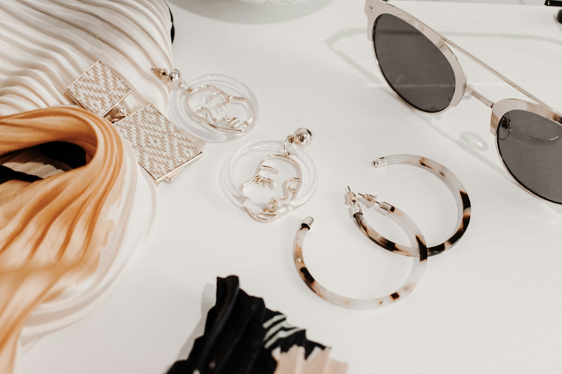 Accessories arranged with a scarf, sunglasses, and jewelry.